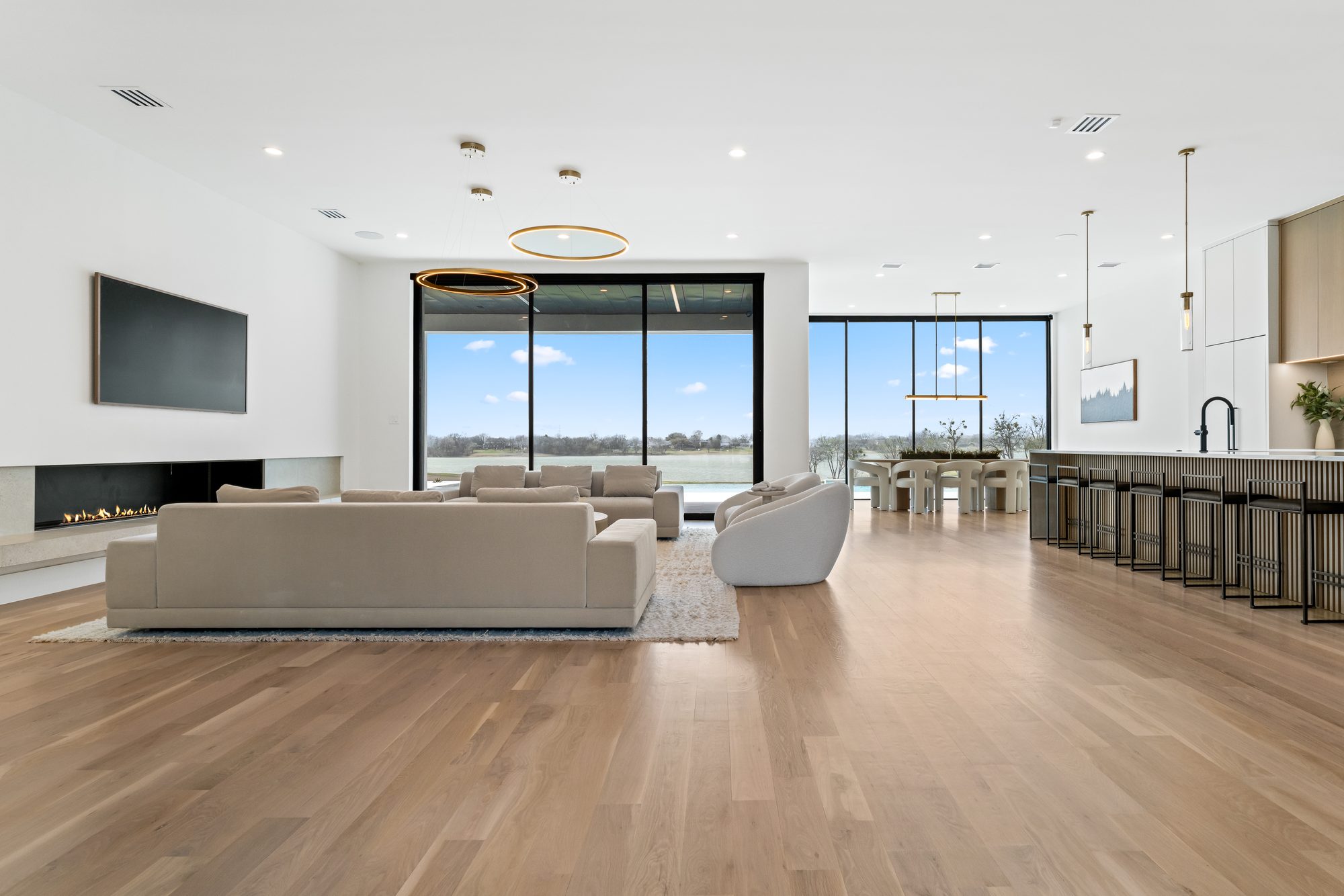 Great room open to the kitchen island, with floor-to-ceiling glass looking out to the pool and the lake