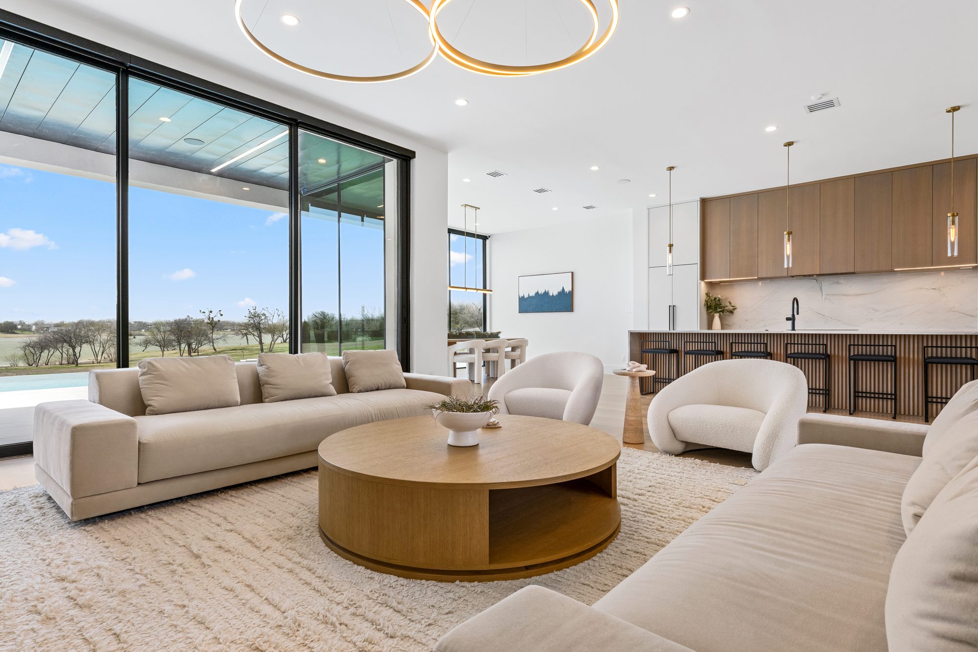 Open living, dining, and kitchen, with the lake through floor-to-ceiling glass